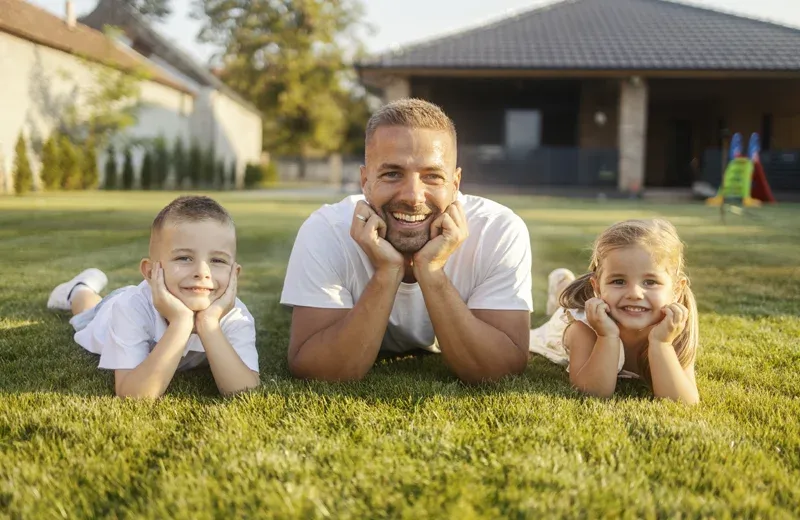 family laying outside on the green healthy grass